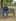 A man sits on the same park bench beside a grey tabby cat, swapped in by the Image Replace tool.