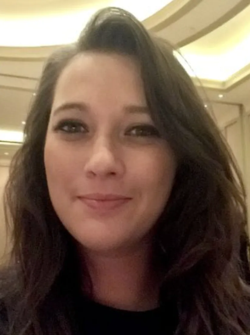 A dark-haired woman takes a close casual selfie under a patio awning before her AI real estate headshots.