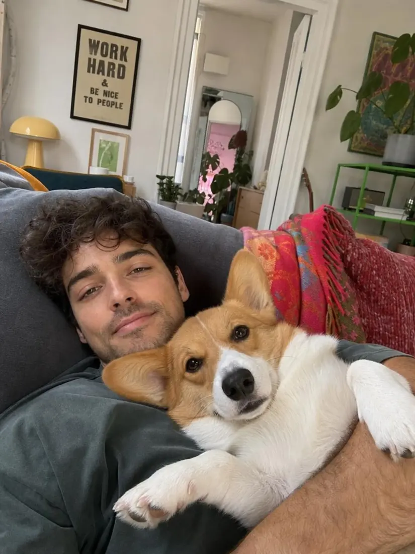 A man holds his corgi on the couch, before the Movie Poster Generator turns them into cartoon movie stars.