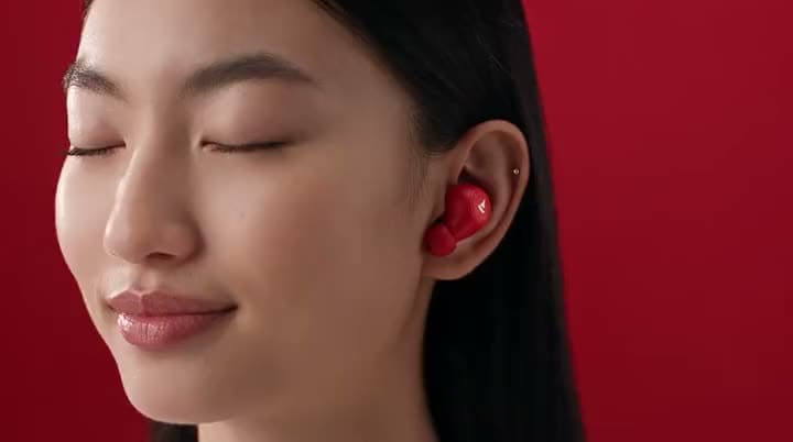 An AI video brand opener: two people wearing red earbuds against a red wall, then the earbuds case lit by a spotlight above the boAt logo.