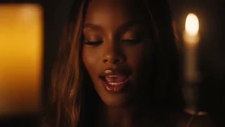 An AI music video close-up of a woman with glossy lips and closed eyes singing in a dim room lit by candles.