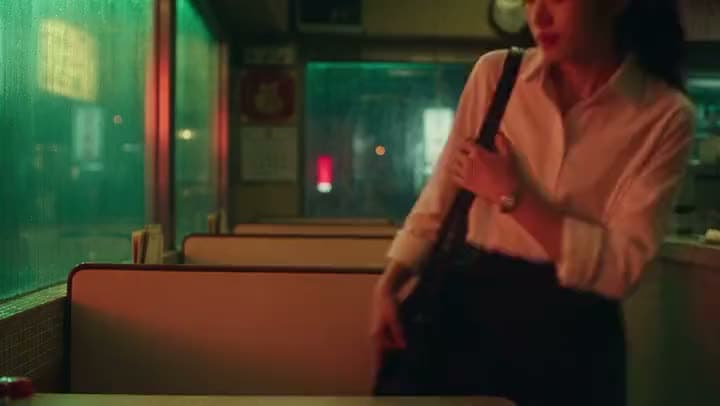 An AI video of a woman in a white blouse clutching her shoulder bag strap by the booths of a neon-lit late-night diner.